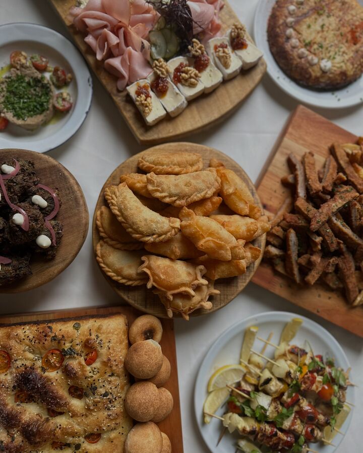 Mesa con tabla de fiambres, empanadas salteñas, focaccia, buñuelos y brochetes